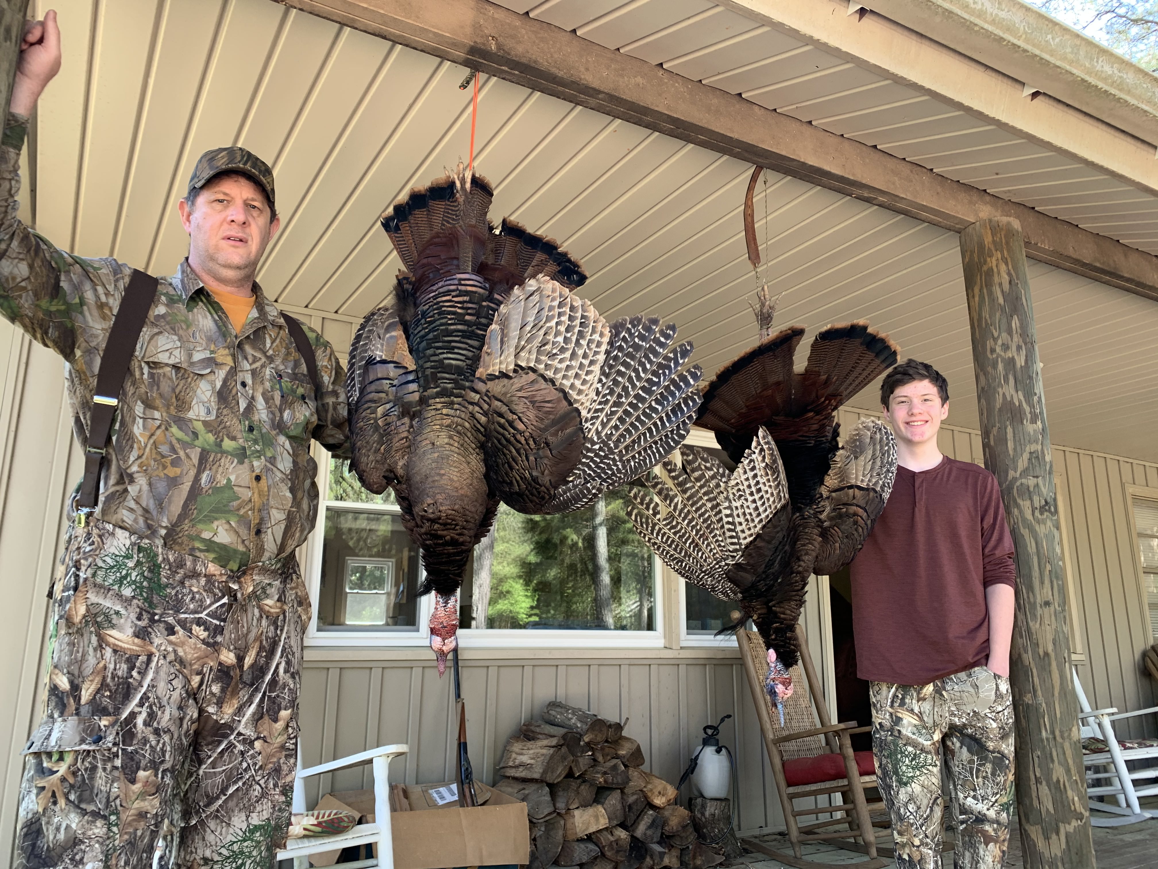 Turkeys hanging with two huntsmen standing by them